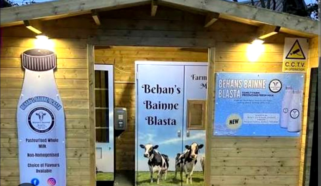 Wooden Behan's Bainne Blasta farm cabin exterior with branded door, milk bottle artwork and Family Farm Producing Fresh Milk signage