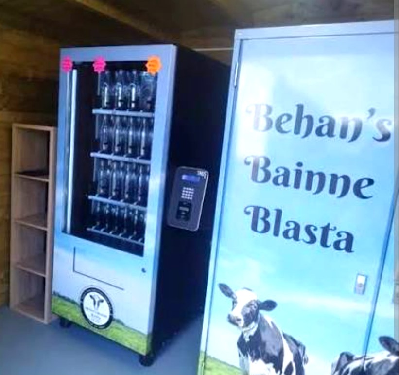 Behan's Bainne Blasta branded vending machine stocked with milk bottles inside the farm cabin